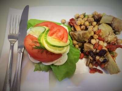 Plated Danish open-face sandwich with tomato, cucumber, lemon, and a chickpea salad.